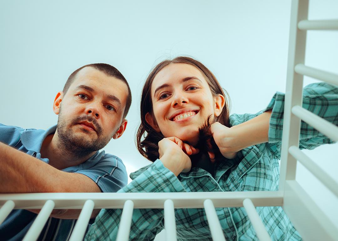 A happy couple looking into their baby's crib.