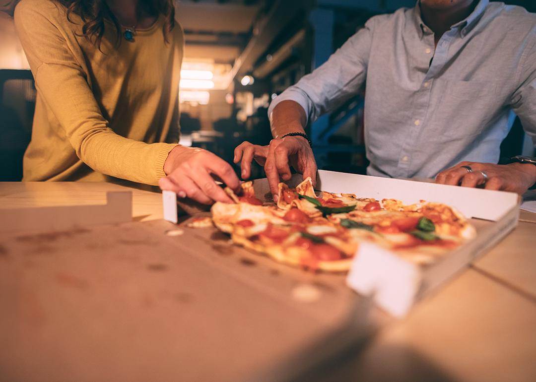 Two people having pizza at night.