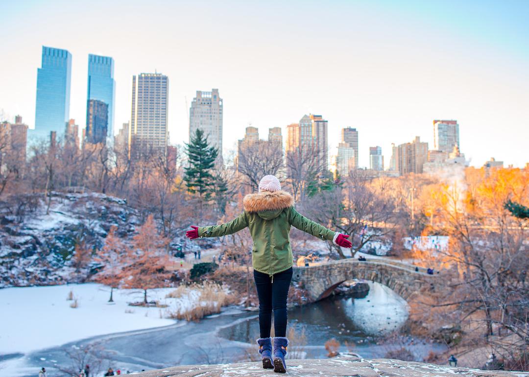 Person enjoying the view of the ice skating rink in Central Park and skyscrapers in New York City during Christmastime.