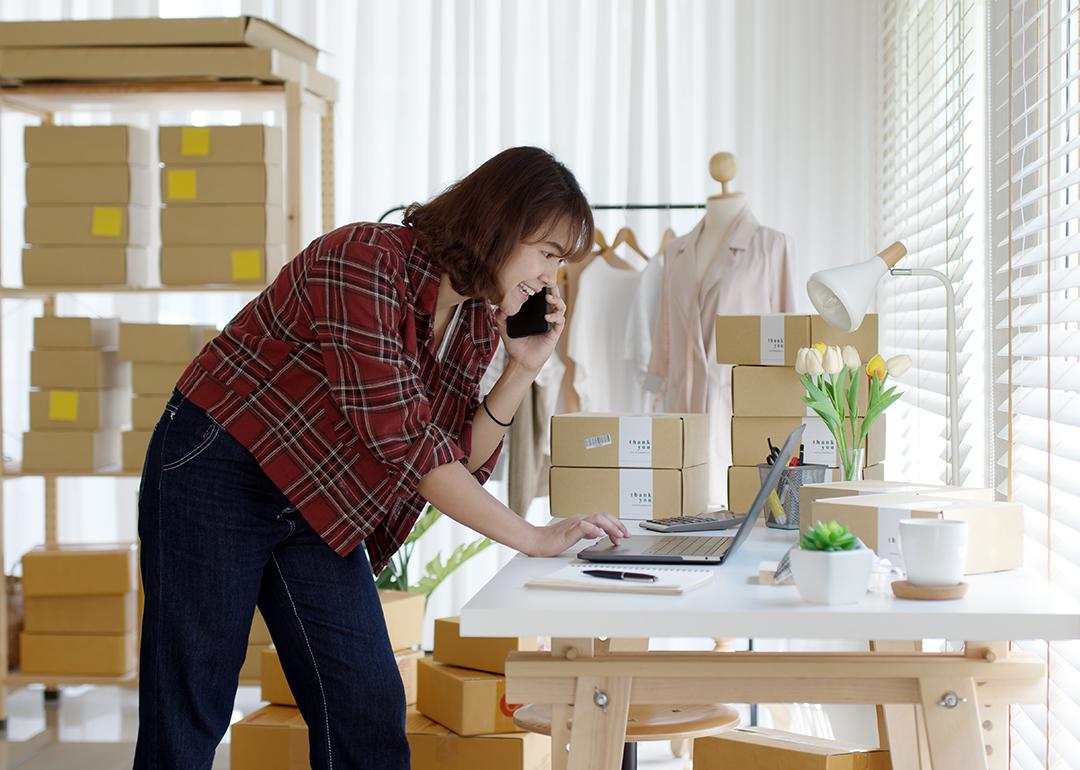 A young female entrepreneur on a call while happily looking at business tasks in a laptop.