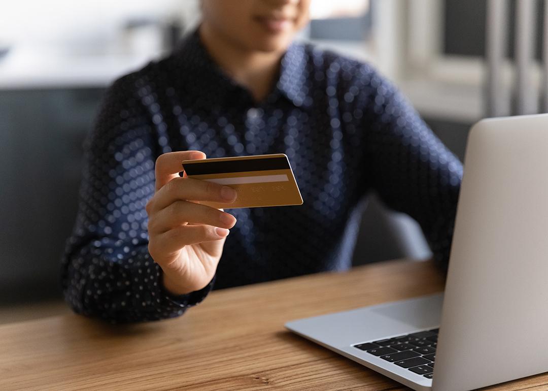 A business professional using a credit card and a laptop.