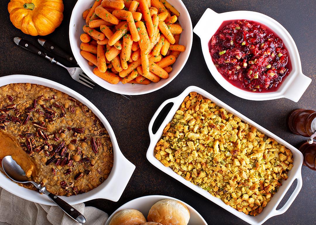 Thanksgiving side dishes such as mashed sweet potatoes, baked vegetables and mac and cheese are laid out on a table.