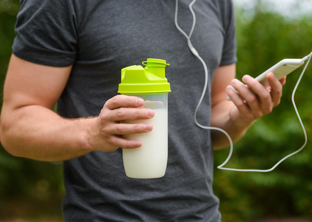 Man on an exercise holding a bottle of supplemental drink.