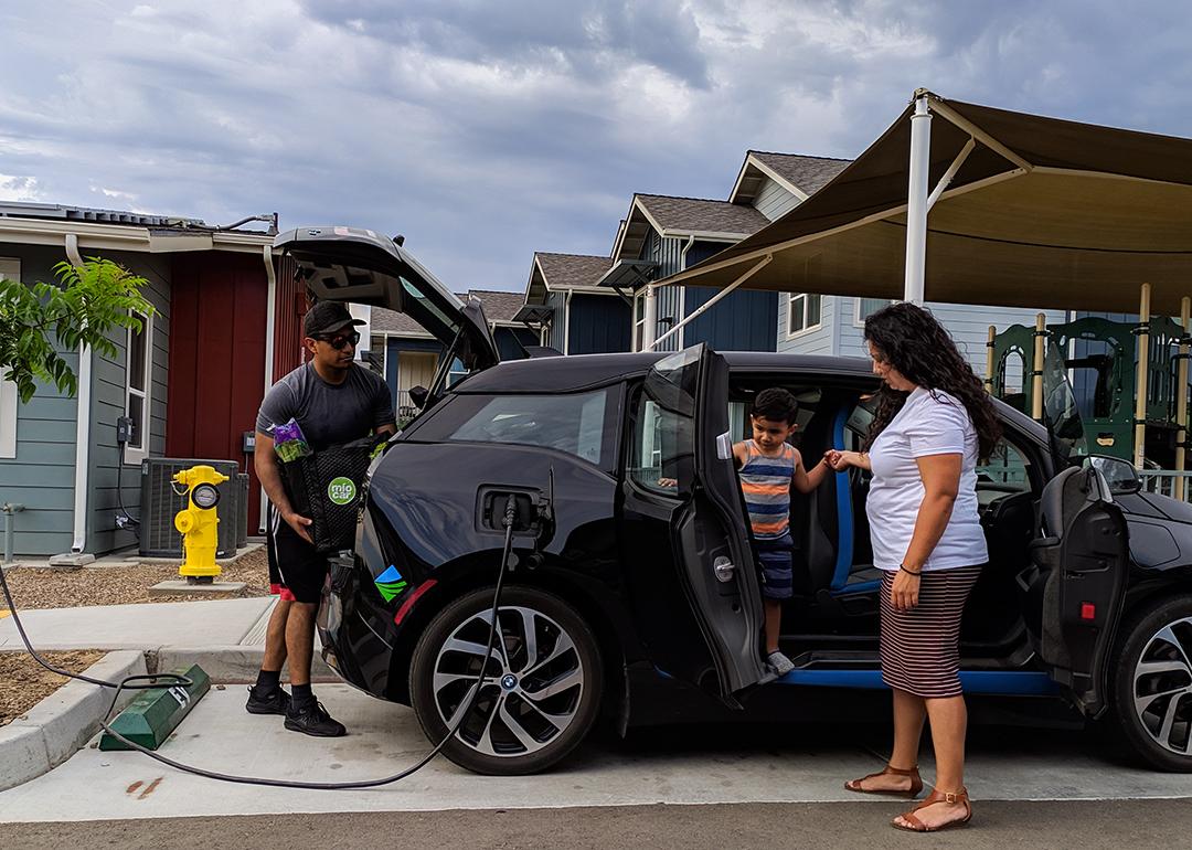 A family of three getting items ready inside a charging electric vehicle.