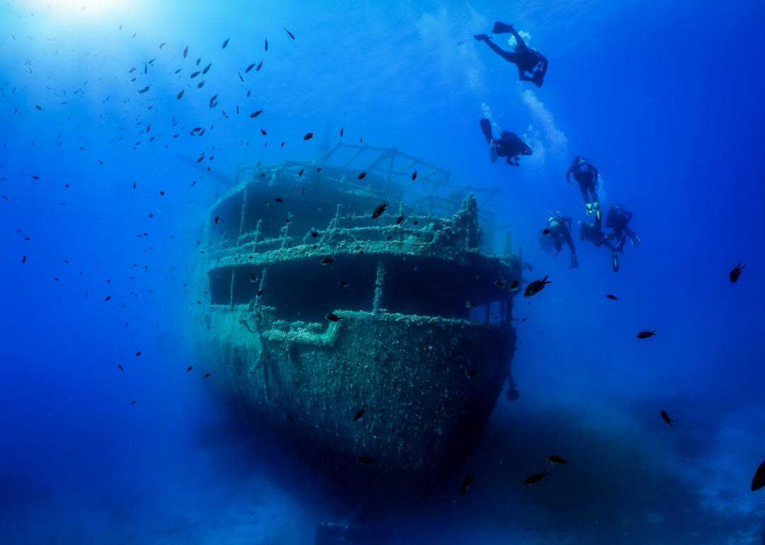 A group of divers explore a sunken shipwreck in the blue, Mediterranean sea at Naxos island, Greece