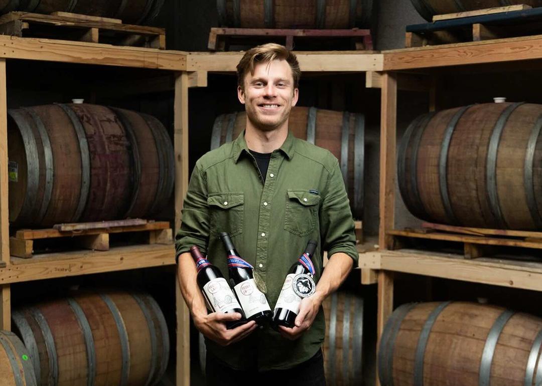 Ben Justman posing with wine bottles in a cellar.