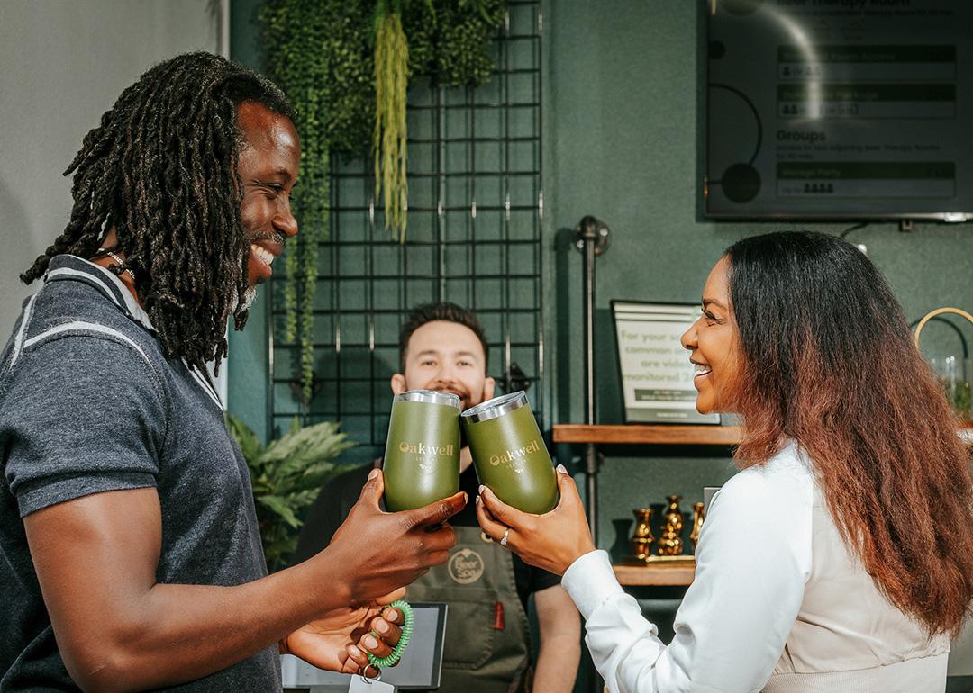 Two people sharing a toast with their Oakwell beer cups.