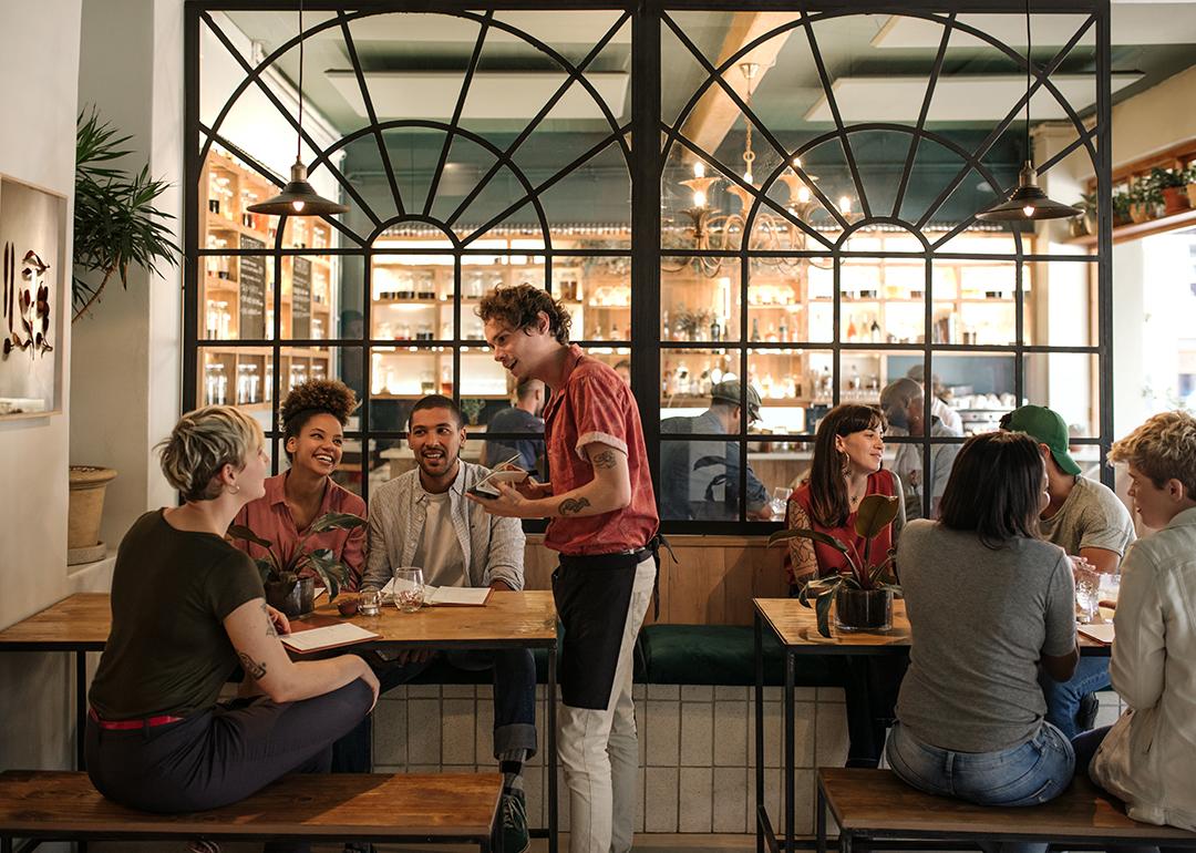 A waiter taking orders from customers in a busy restaurant.