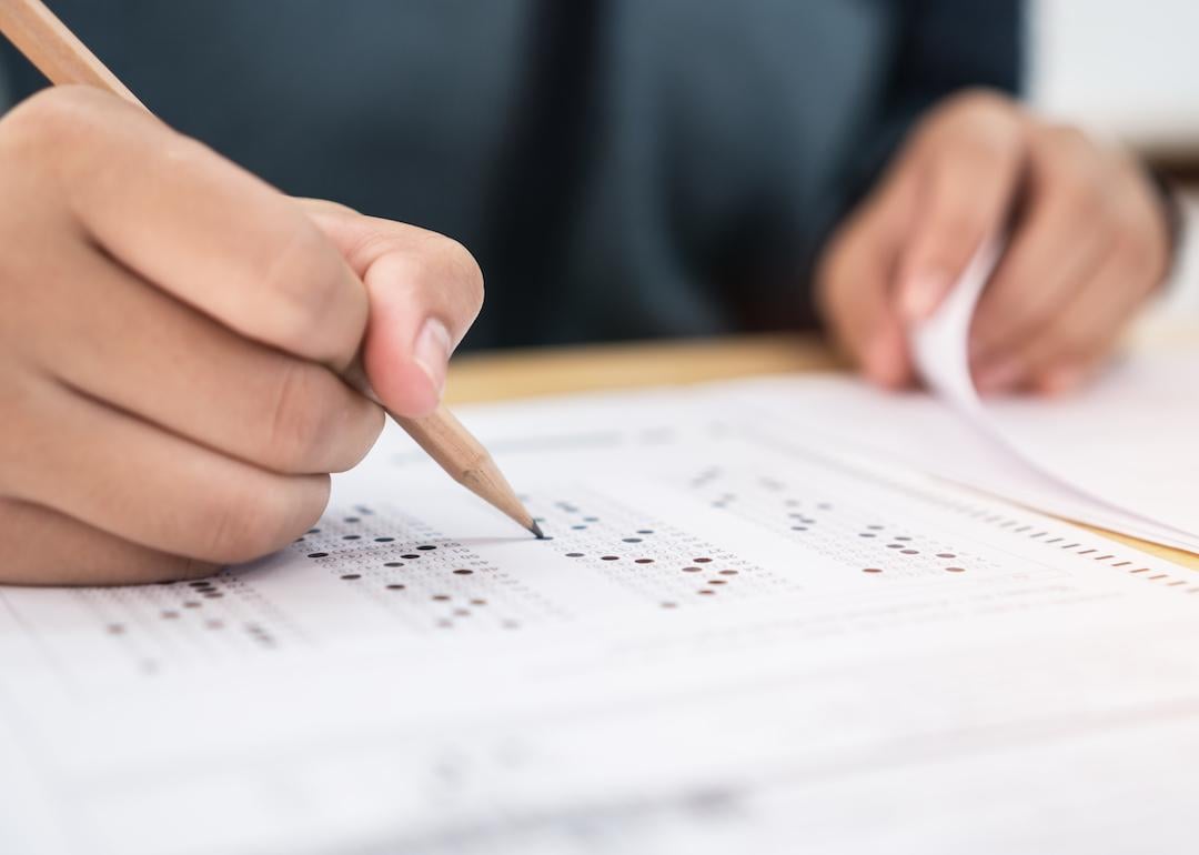 Closeup of student holding a pencil and taking standardized test.