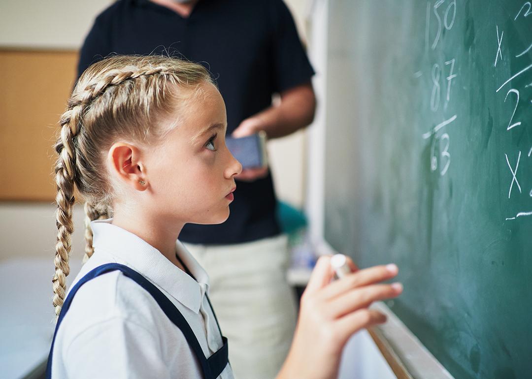 A young girl answering a mathematical exercise using the board in front of a class.