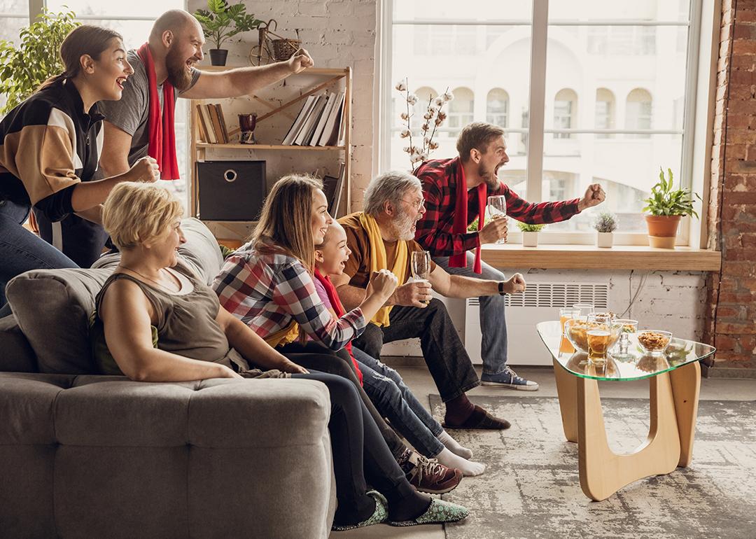 A family excitingly watching sports at home and cheering.