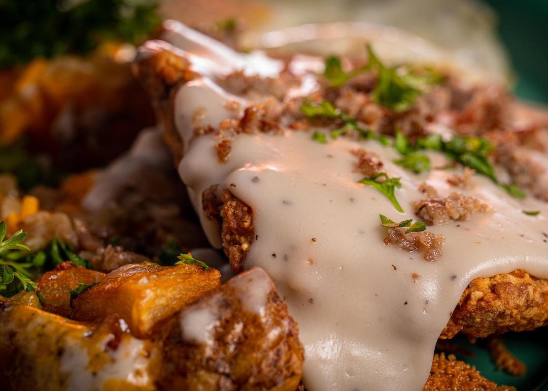 A crispy chicken fried steak with cheesy potatoes, eggs, and gravy.