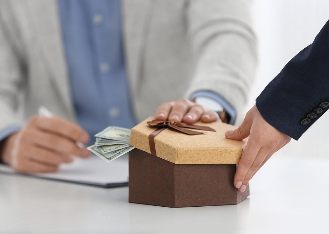 A woman bribing another person in a table in the office.