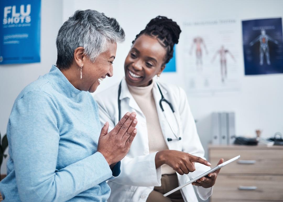 Young doctor reviewing good test results with senior patient on a tablet.