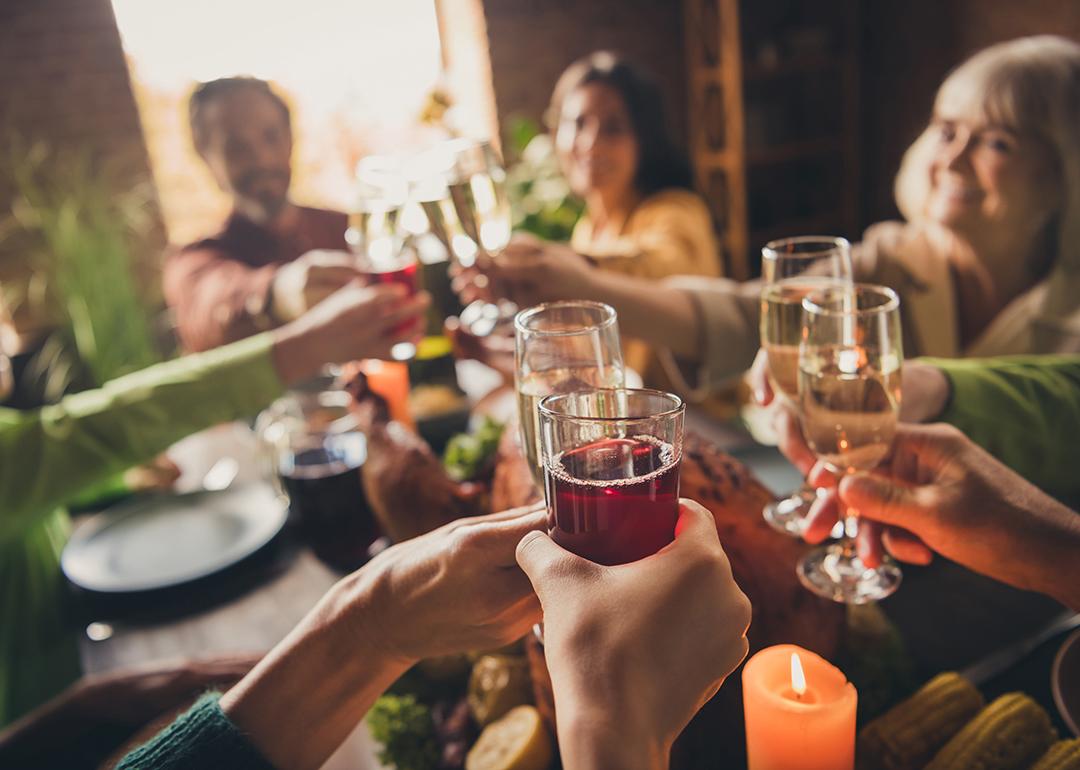 Adults in a family clinking glasses of champagne/wine during a celebration around a table.