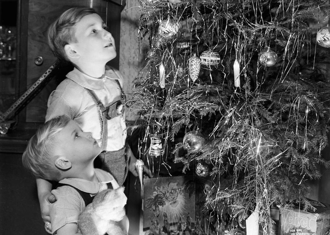 Kids look at a Christmas tree in their living room with candles on it in 1949.