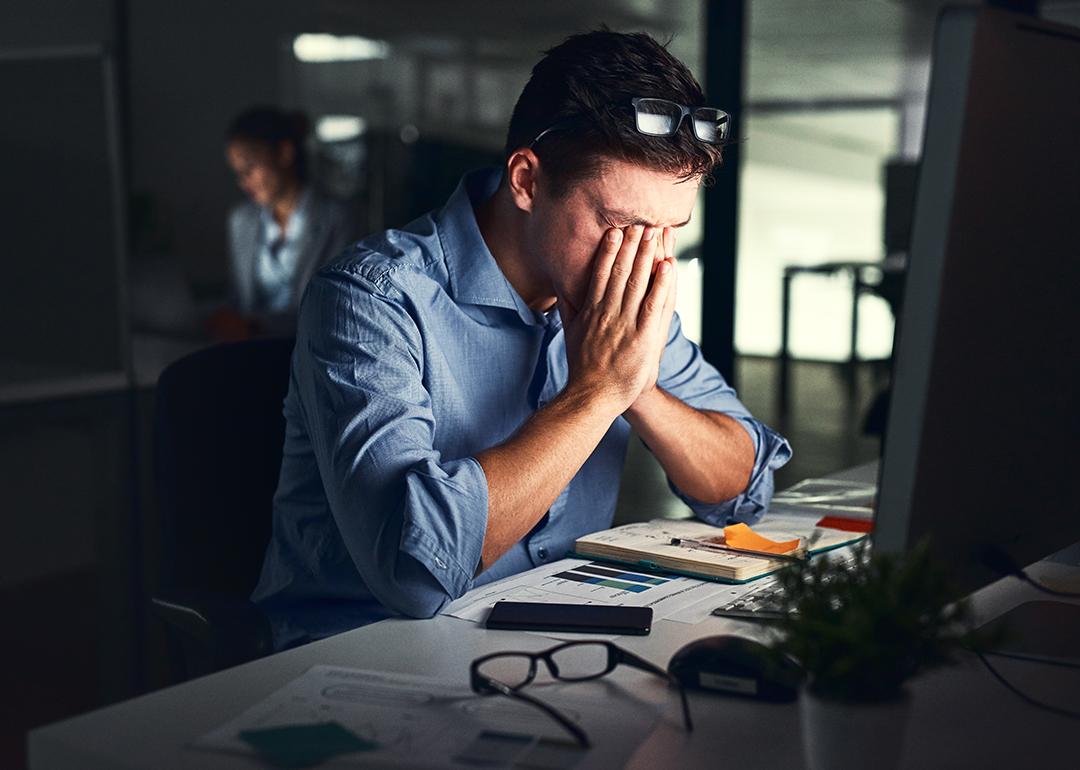 A male employee experiencing strain and stress and working late nights at his office.