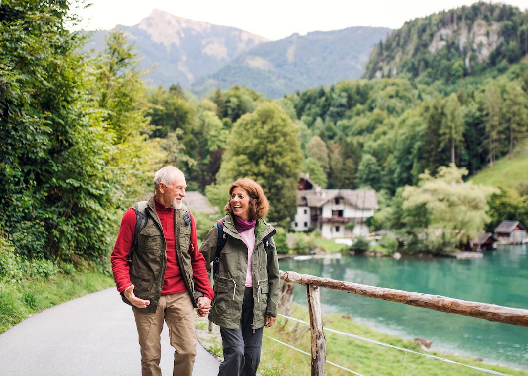 Senior couple hiking near a lake, holding hands, and enjoying the outdoors.