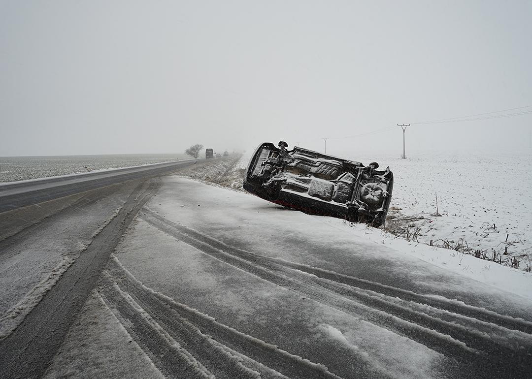 A car lying on its side after an accident in a snowy road.