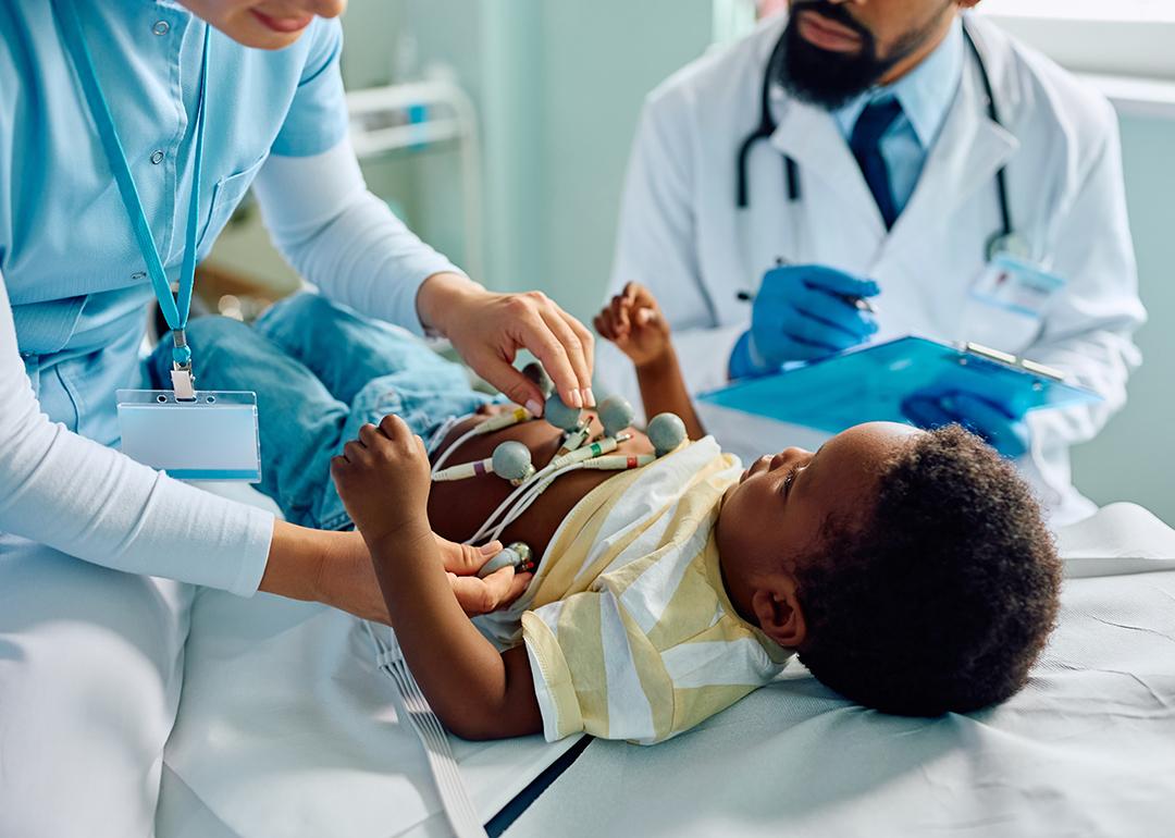 A nurse putting ECG electrode on an infant's chest during a medical examination at a clinic.