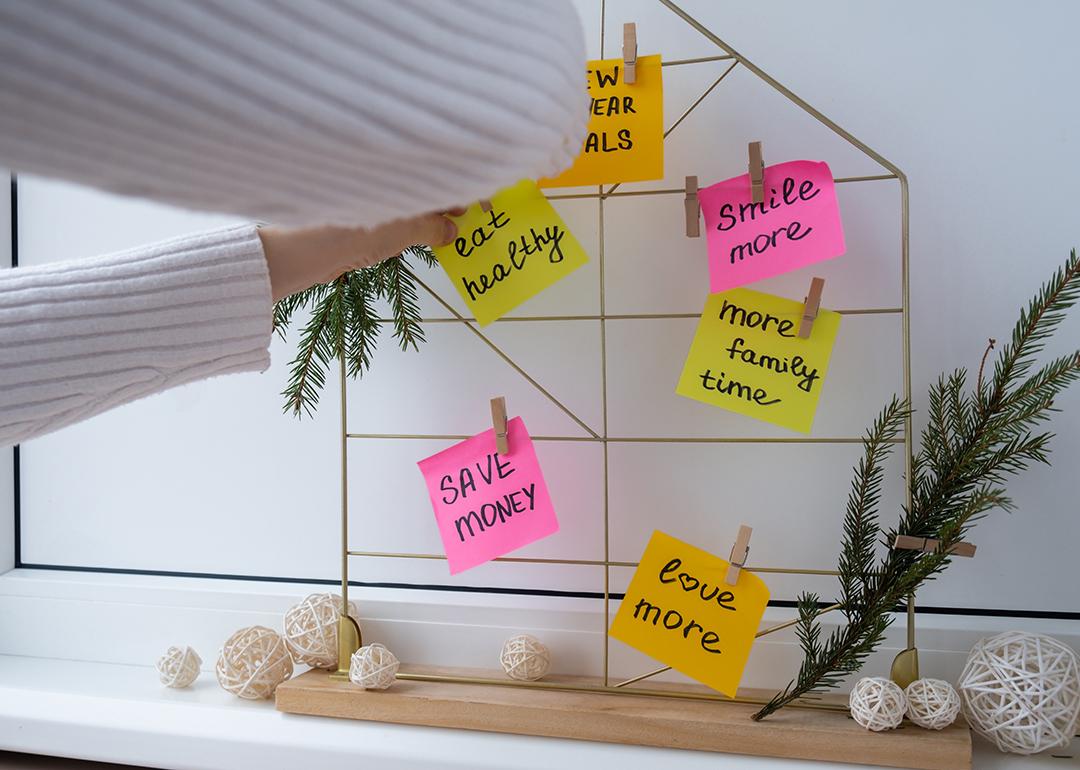 A woman putting up papernotes of New Year's resolutions on a vision board.