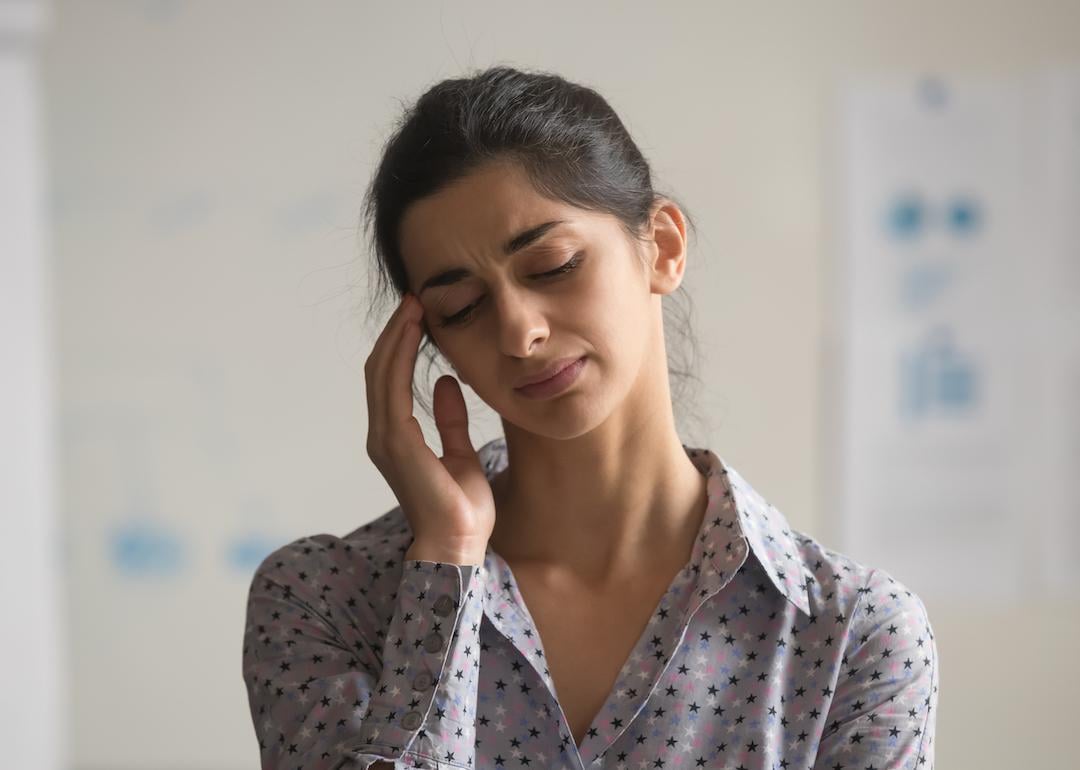 Person closing their eyes and touching their temples.