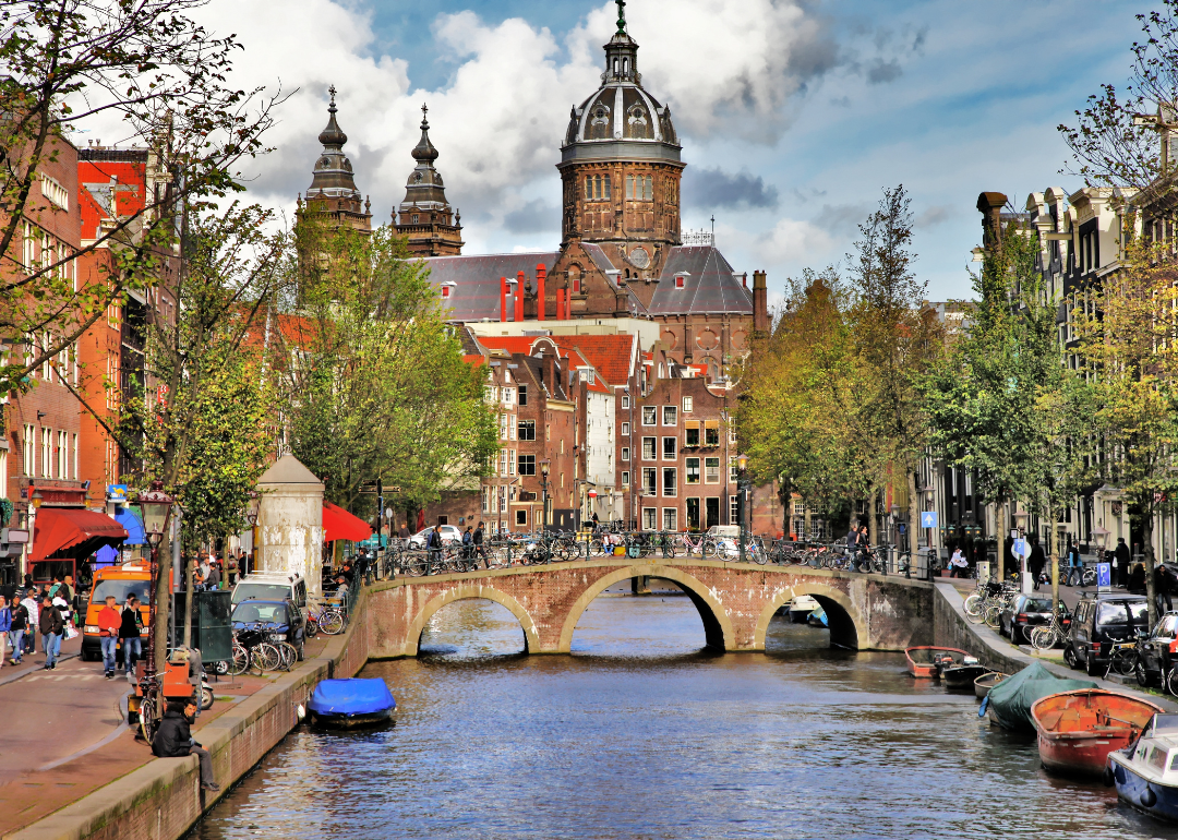 People walking over a bridge and on the streets by a canal in Amsterdam