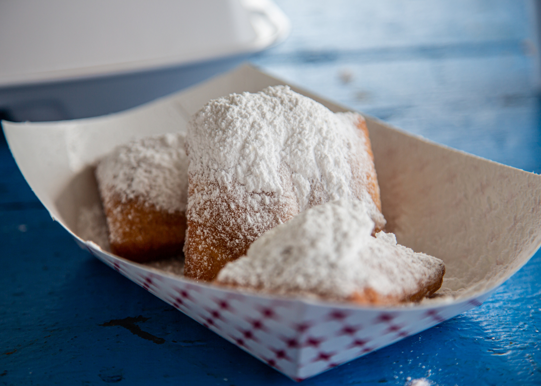 French beignets with powdered sugar on top on blue picnic table