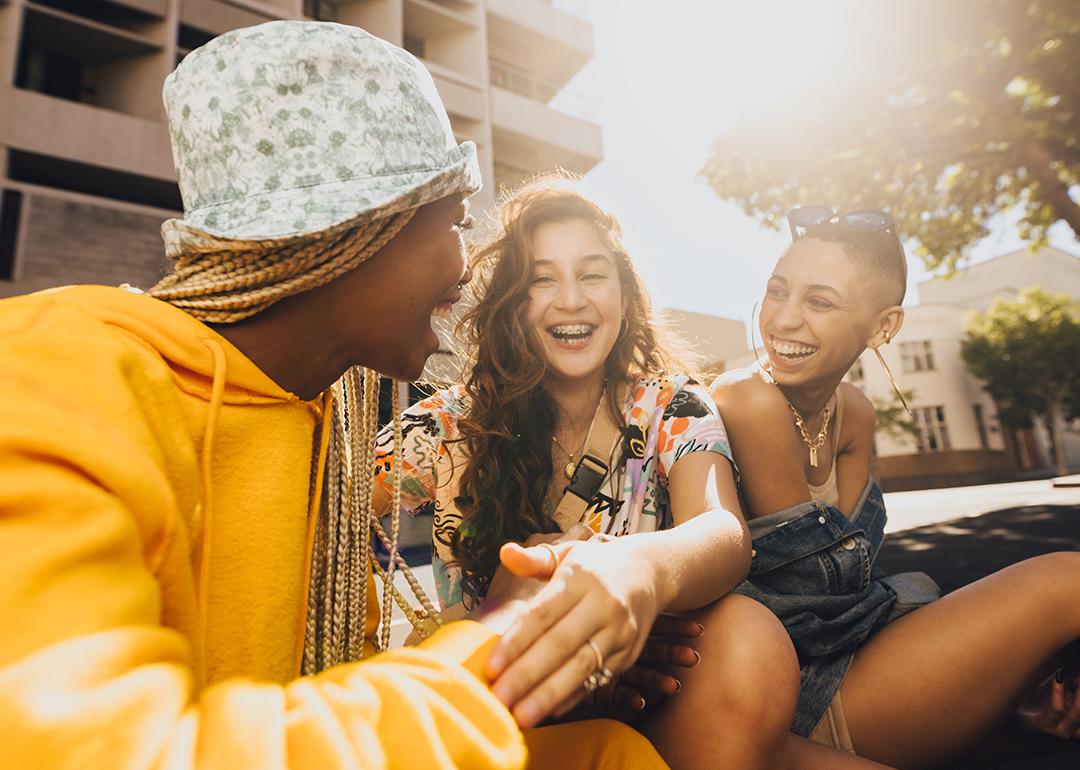 A group of three Gen Z friends laughing and hanging out in the city.