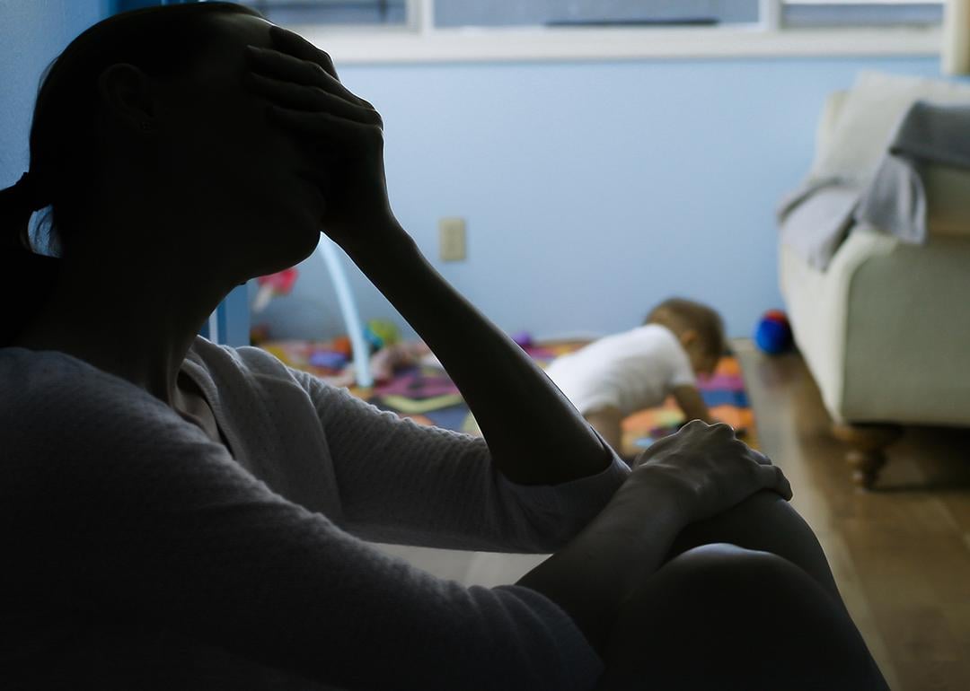 Silhouette of a stressed mother sitting at the corner of her baby's room.