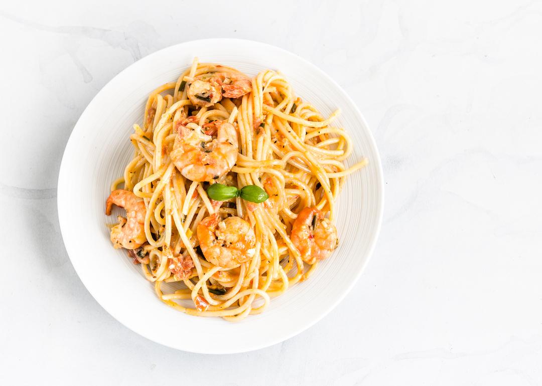 Shrimp scampi pasta on a white plate photographed from directly above.