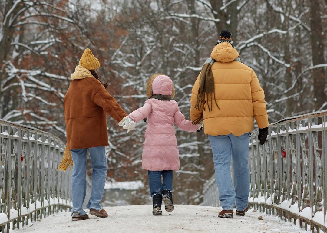 Back view of young family with child walking on bridge together in a small town.