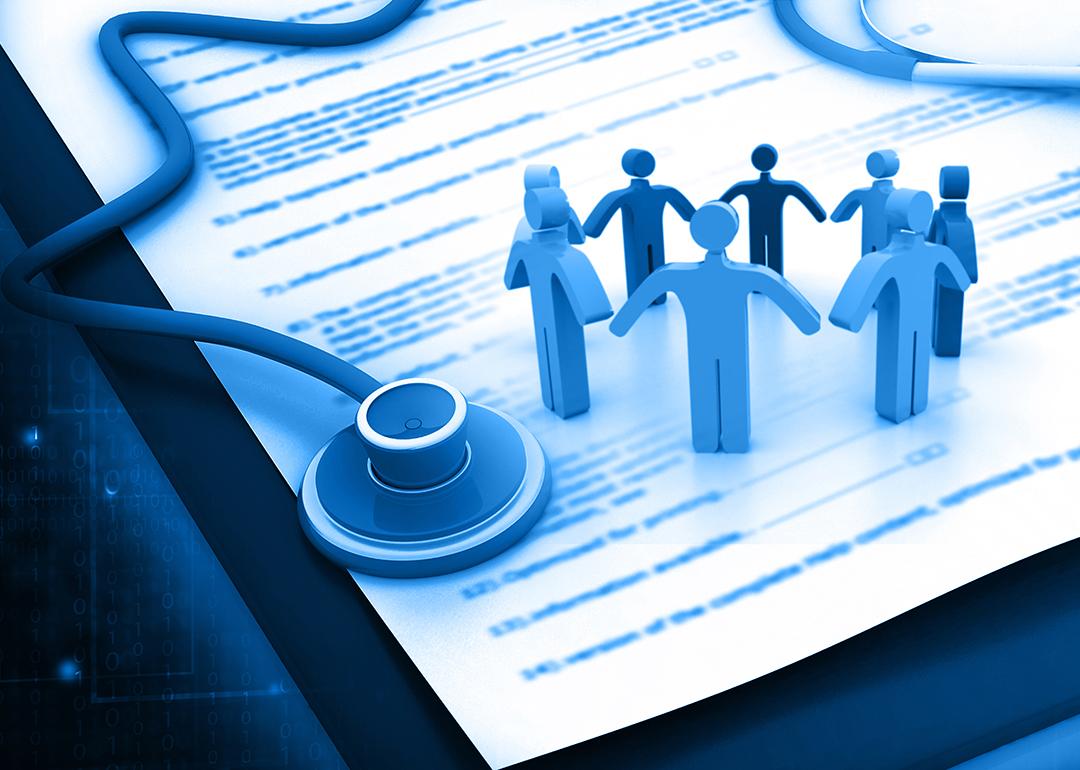 Employee healthcare benefits concept; a stethoscope and figures of people over a health insurance form.