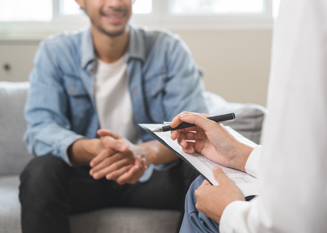 Psychologist takes notes while talking to patient.