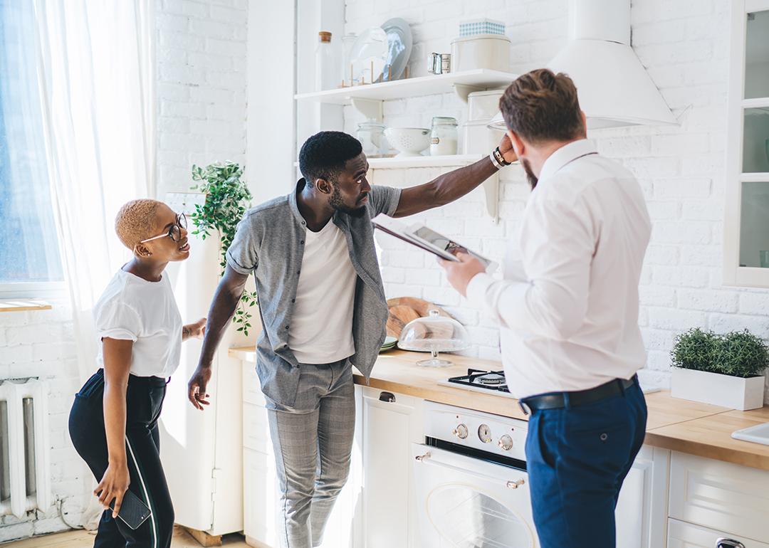 A couple inspects the kitchen of an apartment with a property manager.