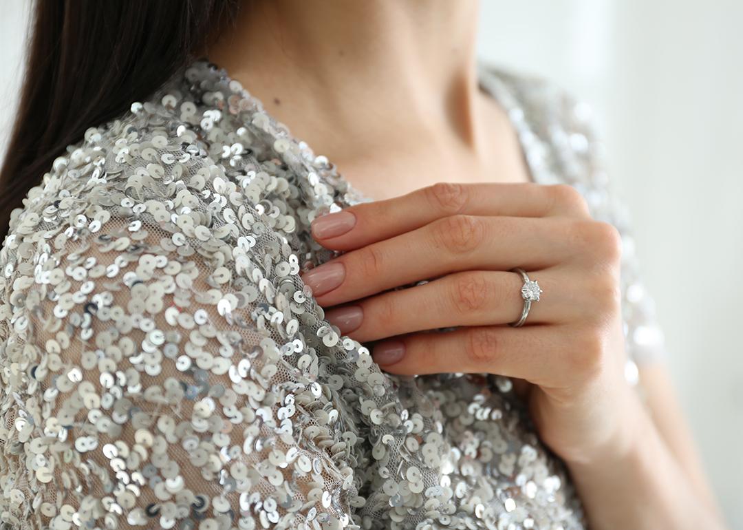 A woman is wearing a silver sequin top to match her engagement ring.