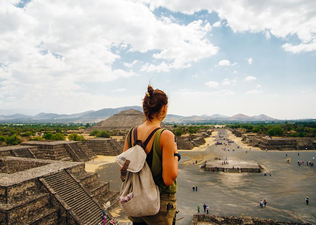 A female American tourist with a backpack enjoys the view from the top of the Moon Pyramid in Teotihuacan, Mexico.