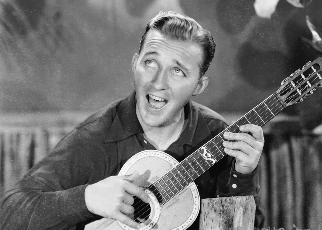 Actor and singer Bing Crosby (1904 - 1977) strums a happy tune on his guitar.