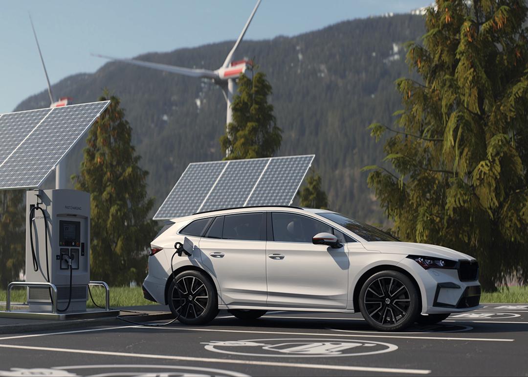 An electric vehicle being charged in a wide lot with a scenic background.