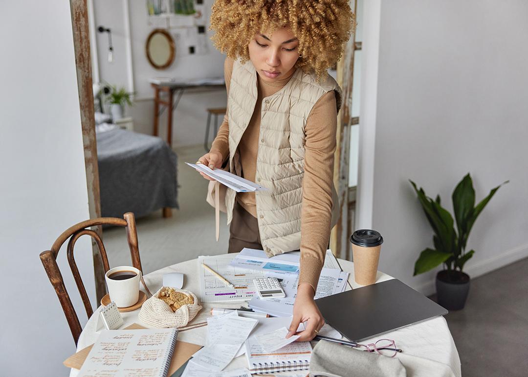 A young woman checks and organizes bills at home.