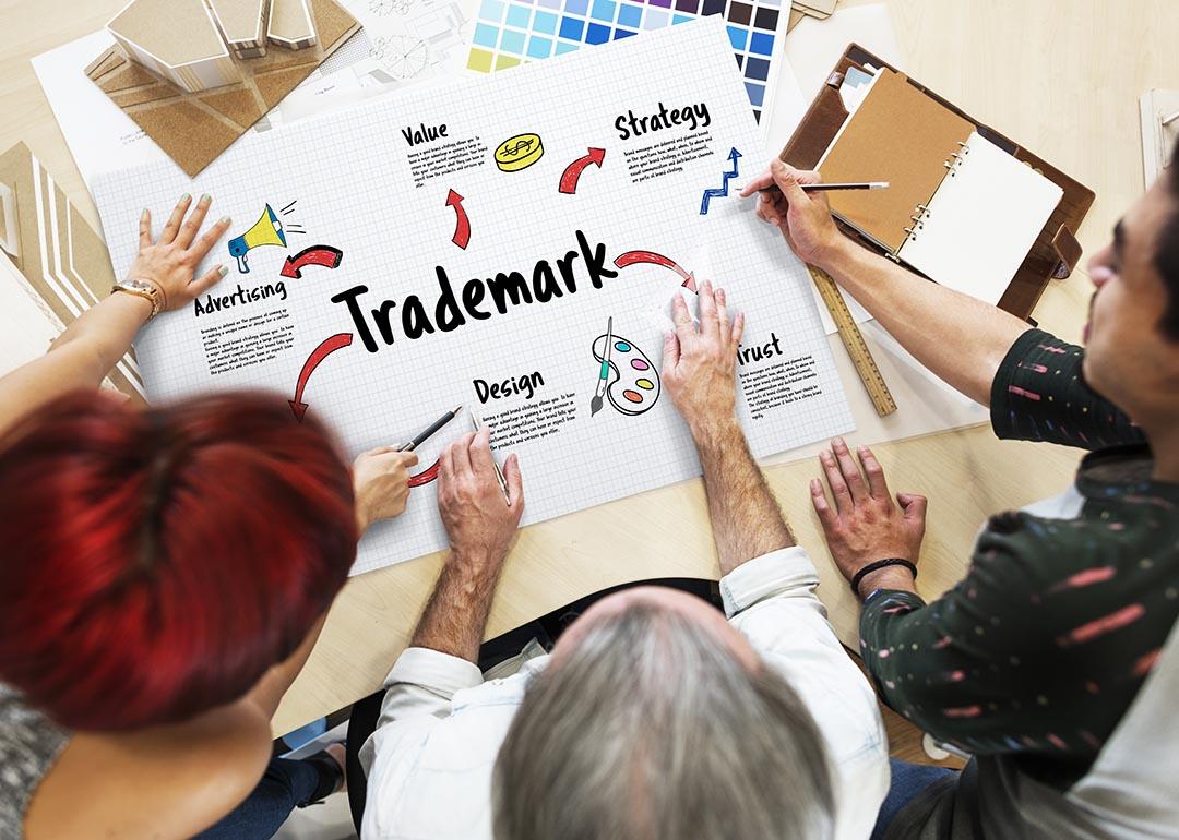 Three people looking at process of marketing and trademarking business, overhead view.