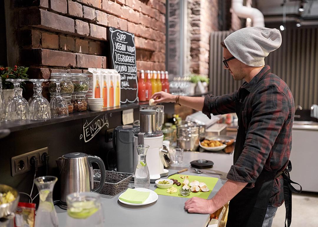 Barman making fruit juice drinks at a local vegan cafe.