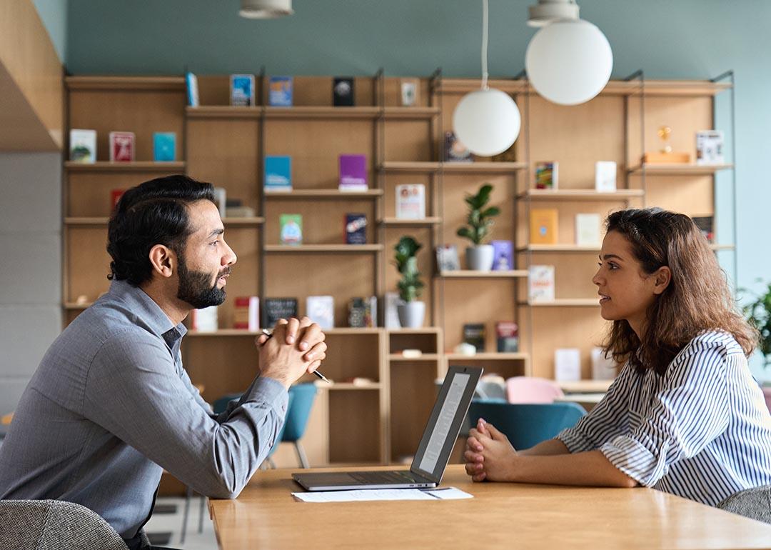 Employer and worker sitting at a wooden table talking.