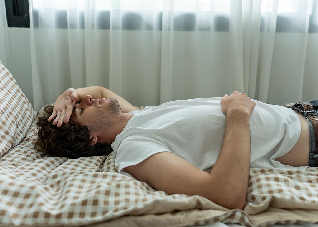 Man lays on bed with low energy during a cold day.