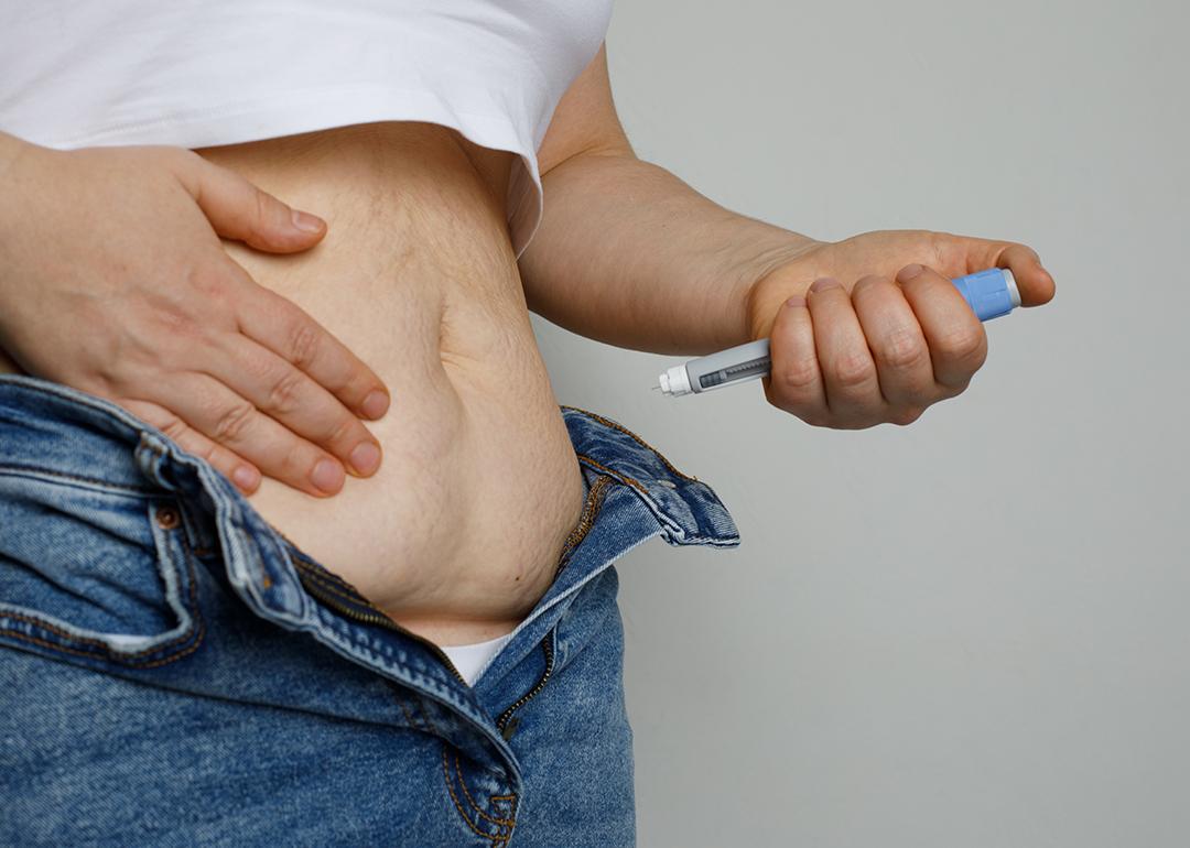 A woman injecting her stomach with an Ozempic (semaglutide) pen.