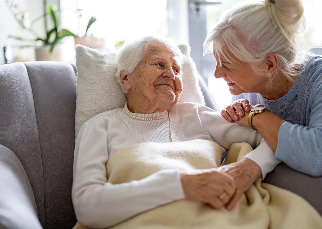 Elderly woman sits with her caregiver at her side.