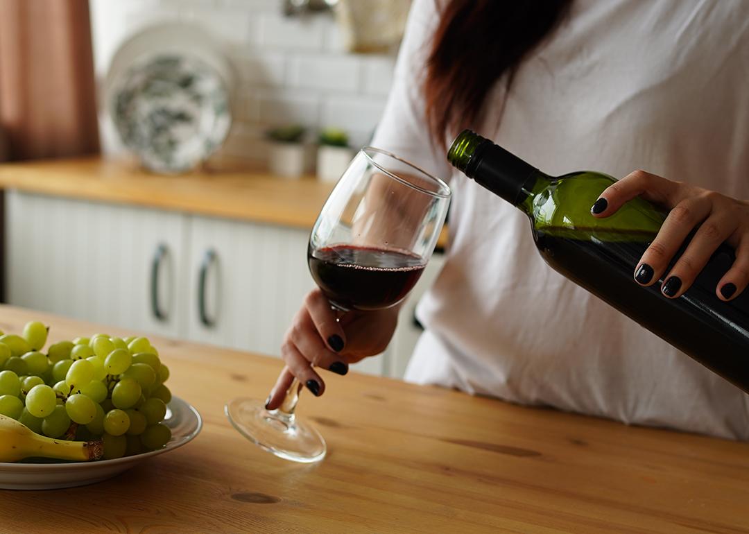 A woman pours a glass of red wine at home.