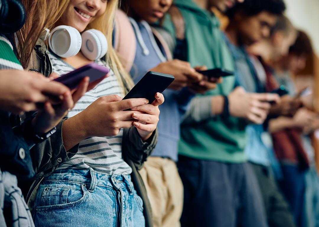 A group of high school students texting using their phones.