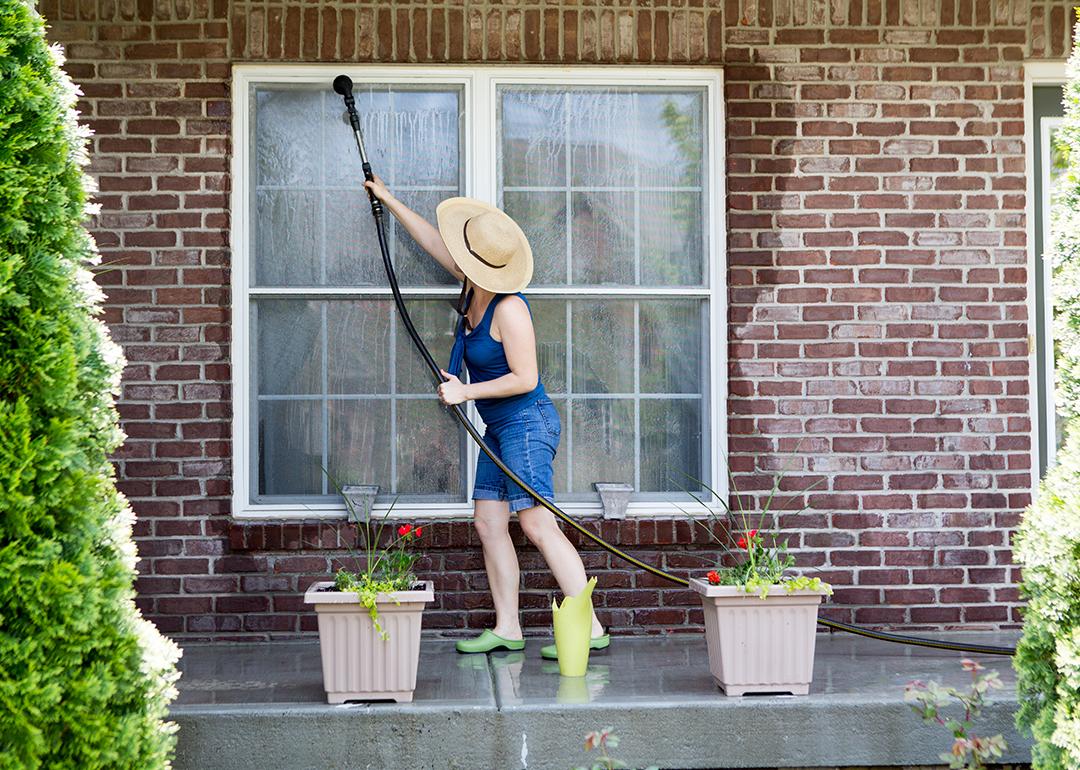 A woman washes the exterior and windows of her house at the start of spring season.