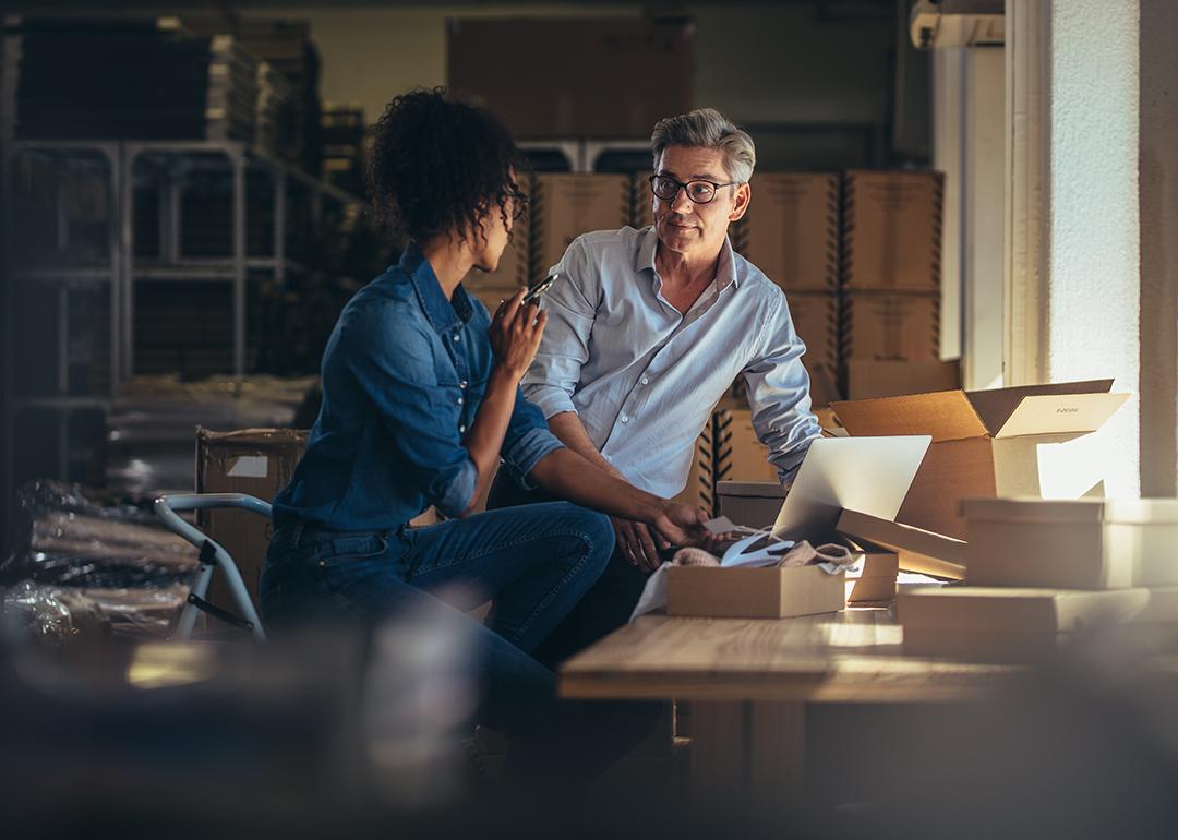 Two business partners having a discussion and using a laptop to check information.